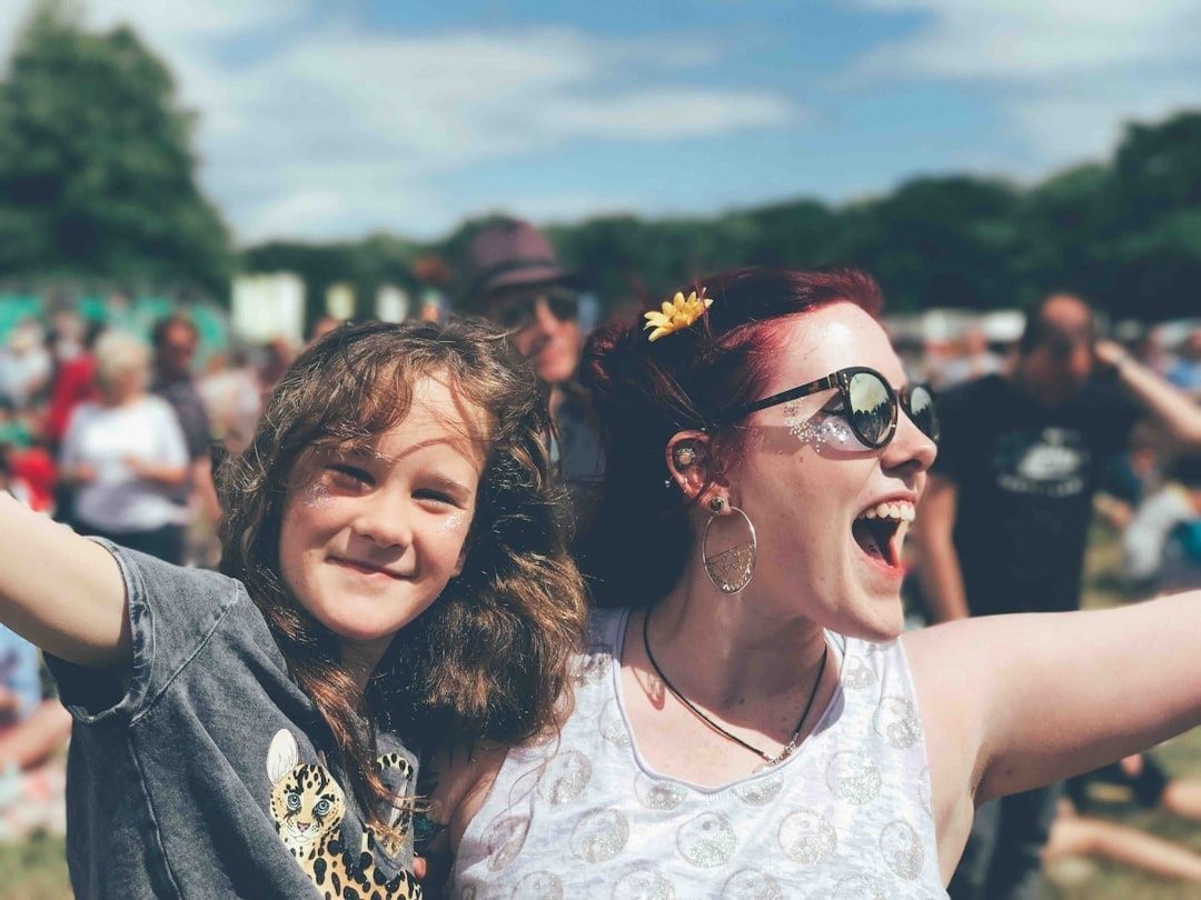 Smilende festivalgæst og barn blandt mange mennesker i solskin
